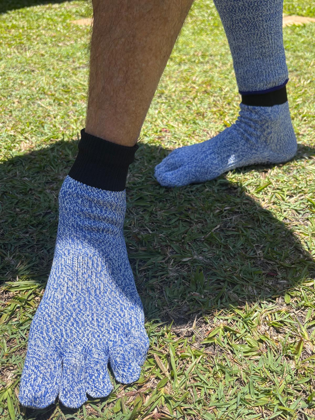 Person wearing blue five-toe socks on grass