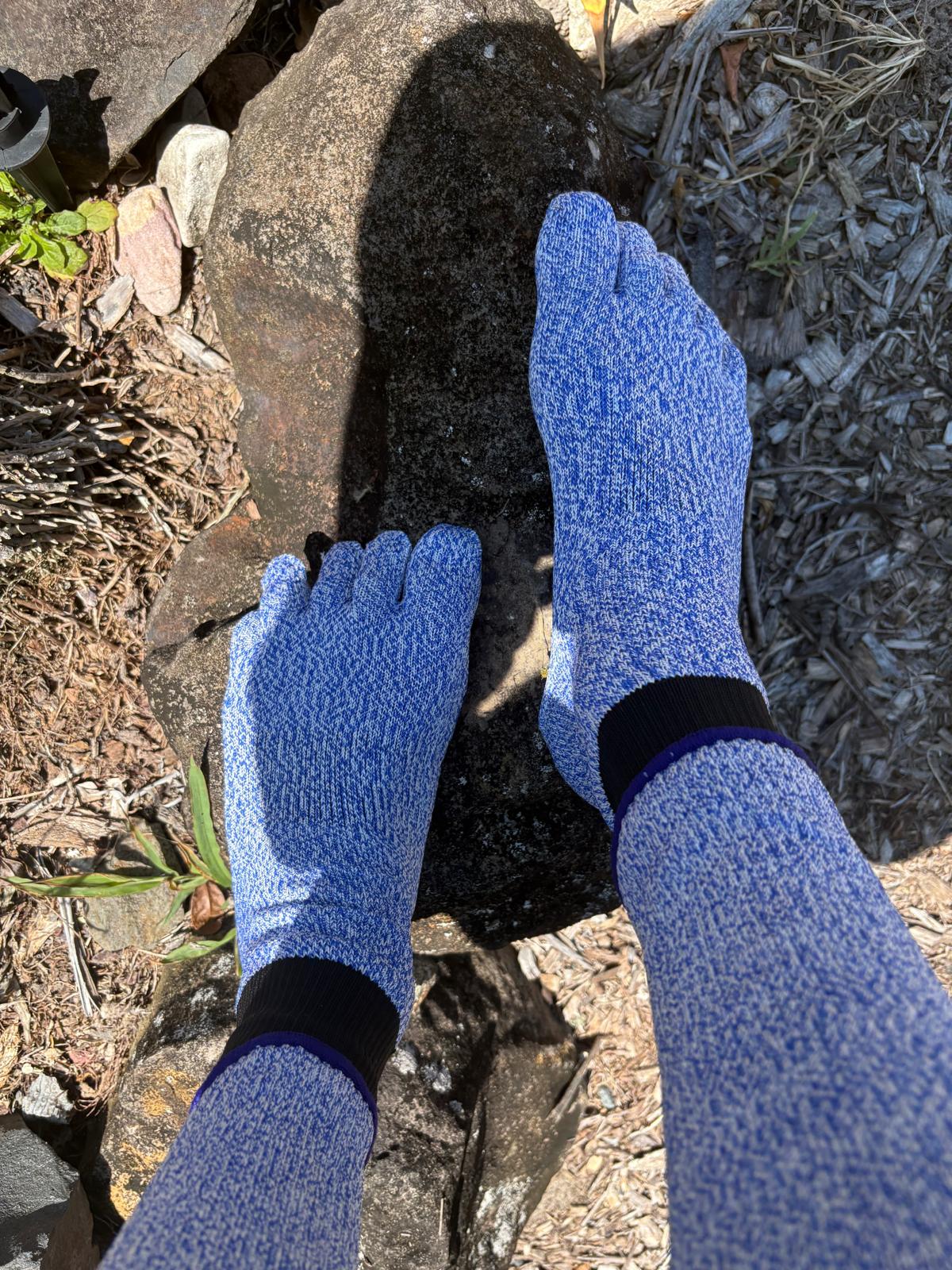 Blue gardening gloves being worn on a person's hands as they work with soil.