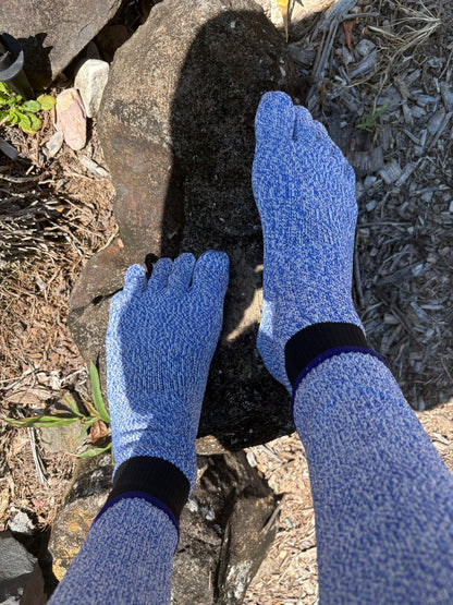 Blue gardening gloves being worn on a person's hands as they work with soil.